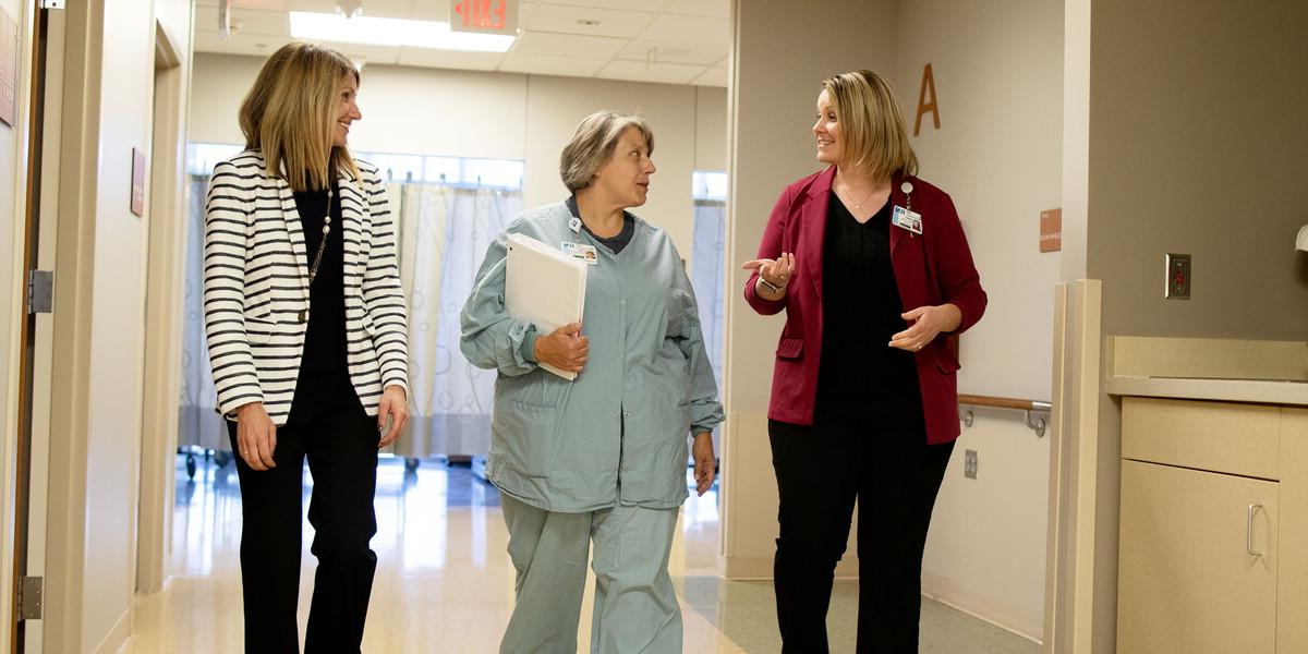Three women walk down a hospital hallway.